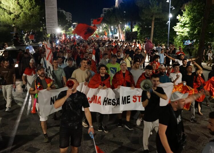 Protesters with Albanian flags and banners march at night in Tirana, as Albania student protests join the Flamingo movement