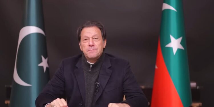 Former Pakistani Prime Minister Imran Khan sits between the Pakistani and PTI flags