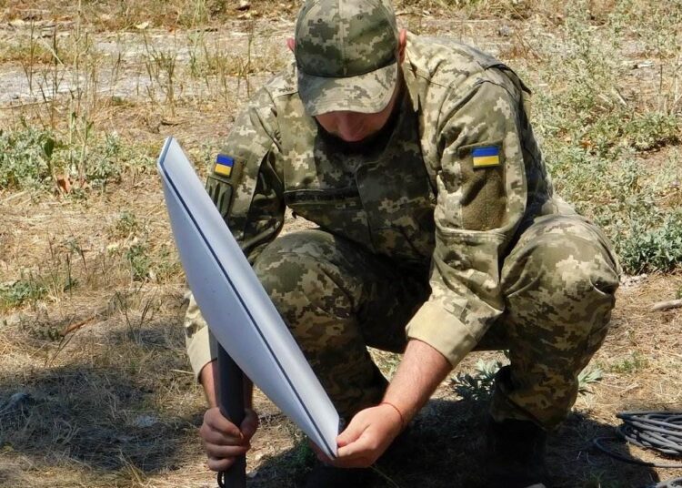 Ukrainian soldier installing a Starlink terminal, as Starshield limits are debated